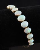 A gold and white opal bracelet, set with eleven graduated oval stones. Starting Price: £200