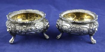 A pair of George III silver bun salts, with embossed foliate decoration, on lion mask knees with paw