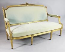 A gilt Louis XVI design open arm settee, with padded arms and fluted tapering legs, W.4ft 11in.