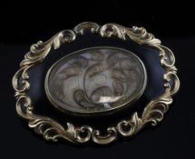 A Victorian gold and black enamel mourning brooch, of shaped oval form with ornate scroll border and