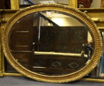 A George III carved giltwood oval wall mirror, the bevelled plate glass and rope twist border, 3ft