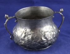 An early Charles II silver porringer, of circular bellied form, with caryatid handles and embossed