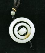 A Chinese pale celadon jade three graduated ring pendant, the central ring with a russet