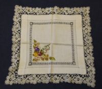 A Continental embroidered table cloth and six napkins, c.1910, with raised work fruit spandrels