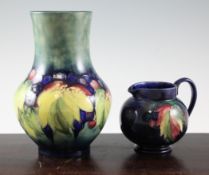 A Moorcroft `Leaf and Berry` vase and a jug, c.1930; the squat baluster vase on a mottled blue and