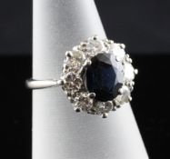 An 18ct white gold and platinum, sapphire and diamond cluster ring, the central oval cut sapphire