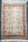 A Turkish Hereke silk rug, with field of scrolling foliage on an ivory ground with multi row foliate