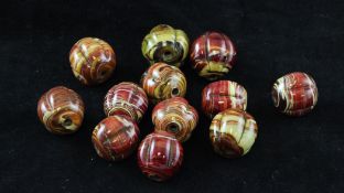 Twelve Chinese moulded realgar glass beads, each 2.1cm.