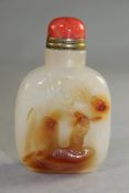 A Chinese agate snuff bottle, carved in relief with a sage on a boat beneath a pine tree to the