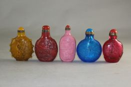 Five Chinese moulded and carved glass snuff bottles, one in simulation of coral and decorated with