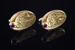 A pair of middle eastern gold and garnet set cufflinks, of oval form with filligree work panel,