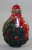 A Chinese overlaid glass snuff bottle, in green glass, carved in relief with two children holding