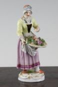 A Meissen porcelain figure of a street vendor, early 20th century, modelled as a woman in 18th