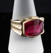 An 18ct gold and synthetic ruby dress ring, with shaped oval stone and fluted shoulders, size U.