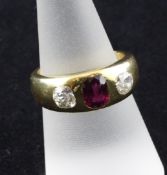 An 18ct gold gypsy set three stone ruby and diamond ring, the oval cut ruby flanked by round
