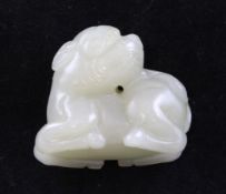 A Chinese pale celadon jade figure of a recumbent lion-dog, the stone with russet inclusions,