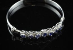 An 18ct white gold, sapphire and diamond set stiff bracelet.