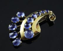 A 1960`s? gold and sapphire brooch, of scrolling design, set with twelve graduated cabochon
