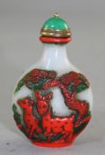 A Chinese three colour glass snuff bottle, carved in cameo in cinnabar red and green glass with