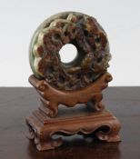 A Chinese grey and russet jade bi disc, carved in relief with stylised dragons, approx. 2.5in.; wood