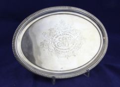 A George III silver oval waiter, with gadrooned border and engraved inscription, on scroll feet,