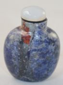 A Chinese sodalite snuff bottle, with black and brown inclusions in the stone, 6.1cm., stopper