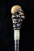An unusual late 19th century Stanhope walking cane, the handle carved as a skull and crossbones on a