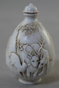A Chinese white glazed porcelain snuff bottle, moulded in relief with three deer below a tree,