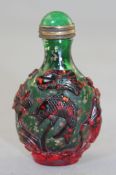 A Chinese ruby and green overlaid glass snuff bottle, carved in relief with carp amid lotus, on a