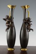 A decorative pair of early 20th century bronzed ewers, with cherub mounts, 16in.