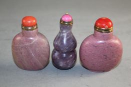 Three Chinese hardstone snuff bottles, two in pink jasper, the third a lavender and grey tinted