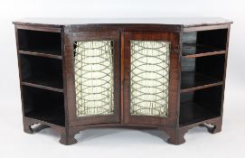 A 19th century concave mahogany side cabinet, with a pair of brass grill doors and open shelves,