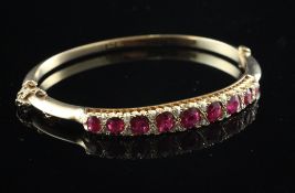 A 15ct gold ruby and diamond stiff bracelet, set with nine graduated rubies.
