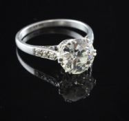 A platinum set solitaire diamond ring, with diamond set shoulders, the round brilliant cut stone