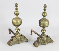 A pair of Carolean style brass fire dogs, with gadrooned and leaf decorated spherical bodies and