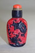 A Chinese blue and red overlaid glass snuff bottle, carved in relief with chi-dragons amid waves,
