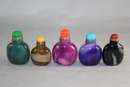 Five Chinese stained agate snuff bottles, in purple, rose, green, black and brown, largest 6.2cm.,