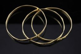 A set of three middle eastern gold bangles, with engraved decoration, unmarked, 33.4 grams.