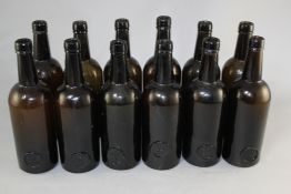 Twelve Trinity College Common Room sealed olive green glass wine bottles, mid 19th century, 7.75in.