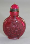 A Chinese ruby glass snuff bottle, carved and moulded in relief with a fisherman on a raft, the