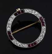 A gold, ruby and diamond set circular brooch, with alternating rows of three rubies and five