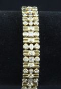 An 18ct gold and diamond bracelet, set with round, emerald and marquise cut stones, 7.25in.