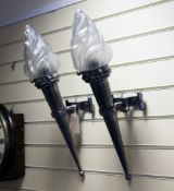 A decorative pair of polished metal wall lights, modelled as a flaming torch with frosted glass
