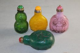 Four Chinese style glass snuff bottles, in four colours, moulded and carved with fish, bats, dragons