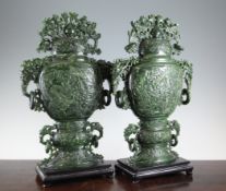 A pair of large Chinese spinach green jade vases and covers, 20th century, elaborately carved in