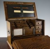 An Edwardian oak writer`s compendium, with fold out writing slope, inkwells and fitted compartments,