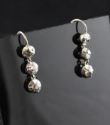 A pair of white gold and three stone diamond drop earrings, with collet set stones, 1in.