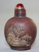 An unusual Yixing pottery snuff bottle, decorated in white slip with pavilions in a rockwork