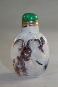 A Chinese agate snuff bottle, carved in relief with a sage in a landscape, carved from the darker