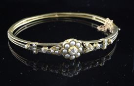 An Edwardian gold, diamond and split pearl set stiff bracelet, with pierced setting, gross 10.6